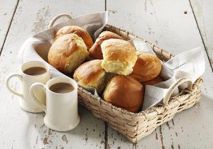 Basket of bread rolls and two mugs.